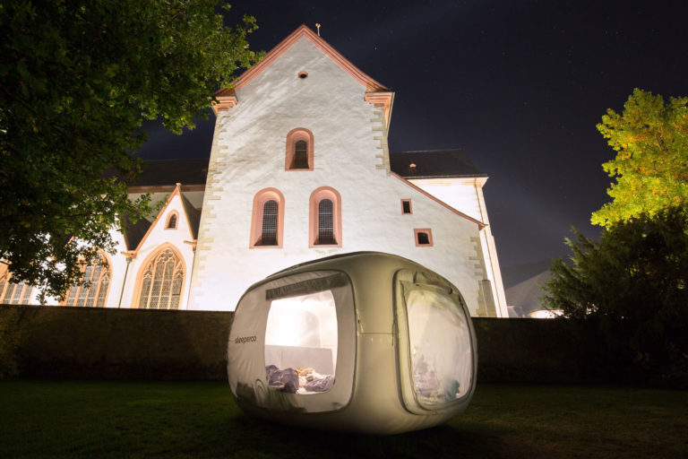 aufgebautes Sleeperoo-Zelt nachts, vor einer angestrahlten Burg